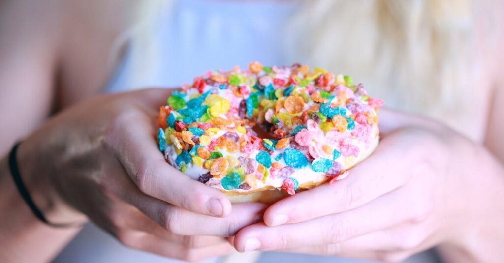 Delicious donut with colorful cereal topping being held by a person, showcasing a fun and vibrant treat.